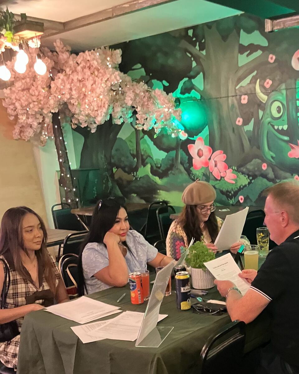 Four guests seated around a table at the trial night, deep in conversation over their clue sheets and drinks.